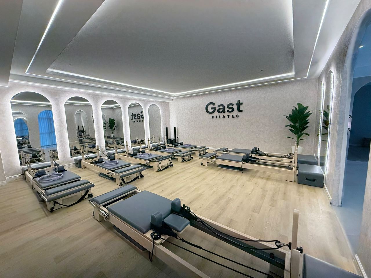 The GAST Pilates studio floor, eight reformers beneath the signed wall